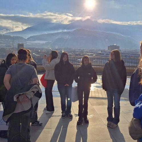 Bild zeigt Schülerinnengruppe auf einer Dachterrasse mit verschneitem Bergpanorama im Hintergrund