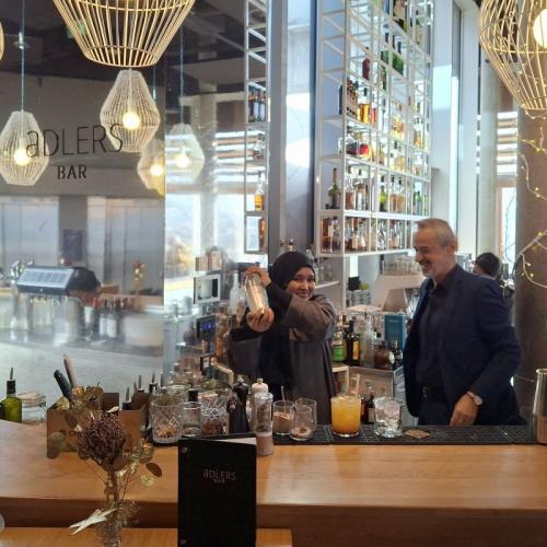 Bild zeigt eine Hotelbar ein Barkeeper mixt Getränke mit einer Schülerin