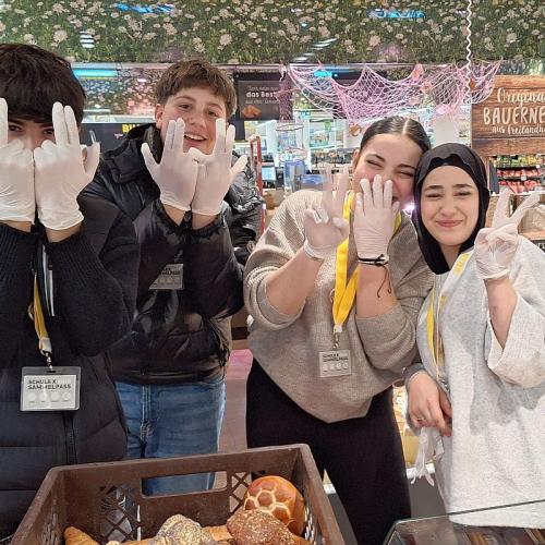 Bild zeigt vier Schüler*innen in einer Billa Filiale die ihre Hände in die Kamera halten. Alle tragen Einweghandschuhe