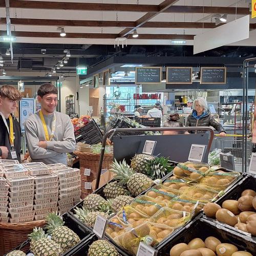 Bild zeigt 3 Schüler vor dem Regal mit verschiedenen exotischen Früchten