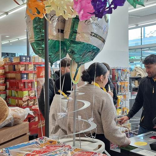 Bild zeigt einen Kassenmitarbeiter in einer Billa Filiale wie er Schüler*innen etwas erklärt.