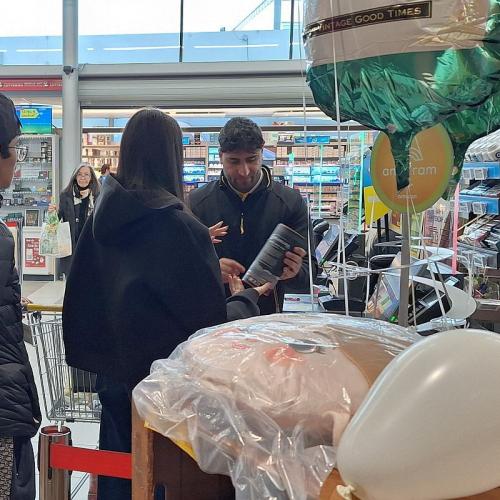 Bild zeigt einen Kassenmitarbeit von Billa wie er einer Schülergruppe etwas erklärt.