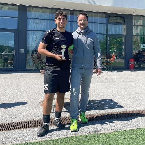 Bild zeigt einen Schüler in Fußballdress mit einem Pokal und daneben einen Lehrer