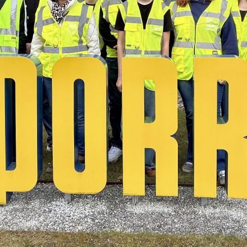 Bild zeigt eine Schülergruppe mit gelben Warnwesten inter dem Logo der Firma PORR