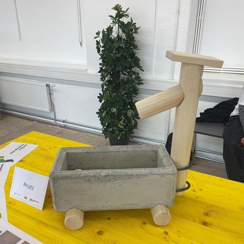 Bild zeigt einen kleinen Brunntrog aus Beton und eine Brunnensäule aus Holz