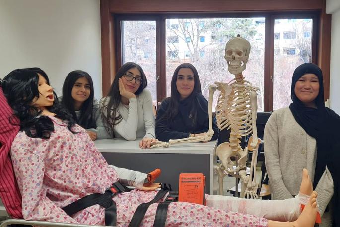 Bild zeigt vier Schülerinnen der Pflegegruppe im Vordergrund ist die neue Pflegepuppe Sam und das Skelett Jack