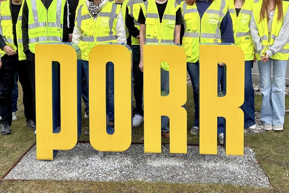 Bild zeigt eine Schülergruppe mit gelben Warnwesten inter dem Logo der Firma PORR