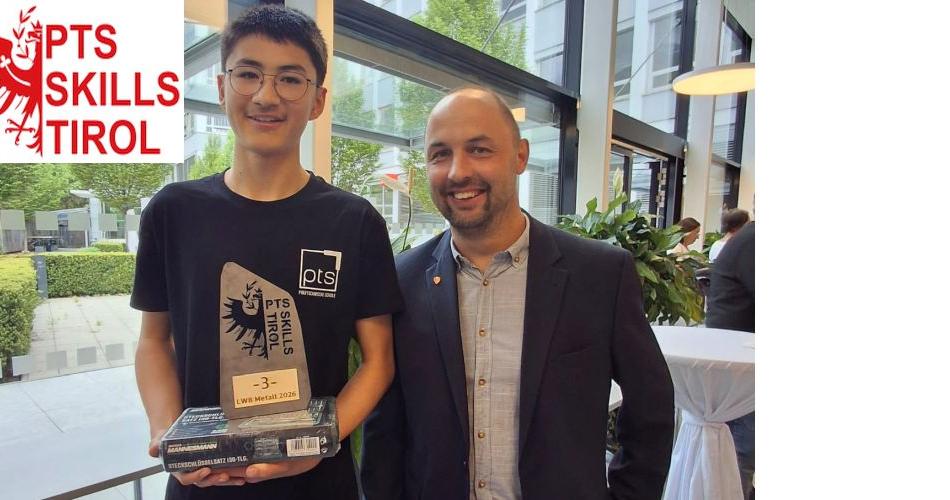 Bild zeigt einen Schüler und einen Lehrer. Der Schüler hält den Preis für den 3. Platz in Metalltechnik in der Hanb