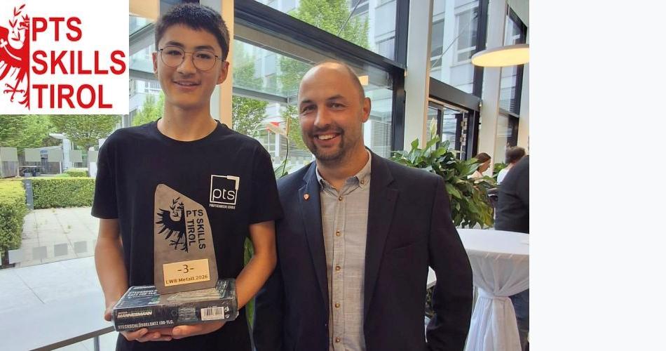 Bild zeigt einen Schüler und einen Lehrer. Der Schüler hält den Preis für den 3. Platz in Metalltechnik in der Hanb