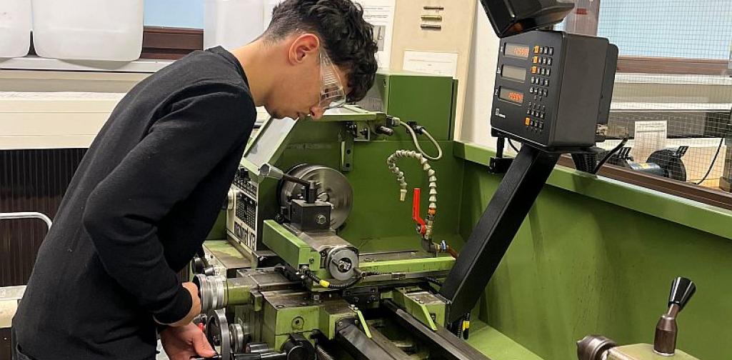 Metall_1_25 Bild zeigt einen Schüler bei einer Maschine in der Metallwerkstätte
