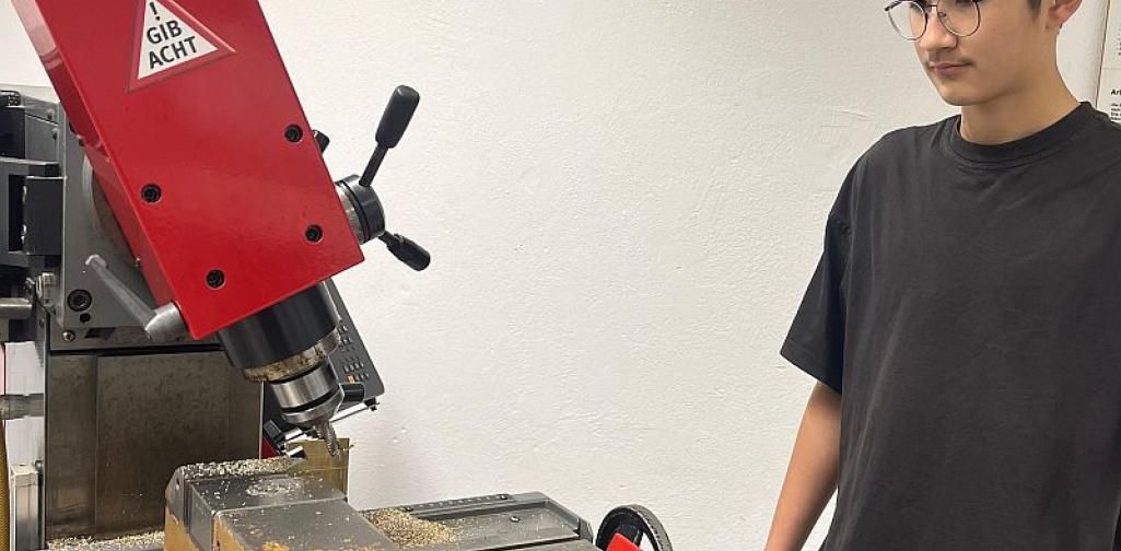 Metall_2_25 Bild zeigt einen Schüler bei einer Maschine in der Metallwerkstätte