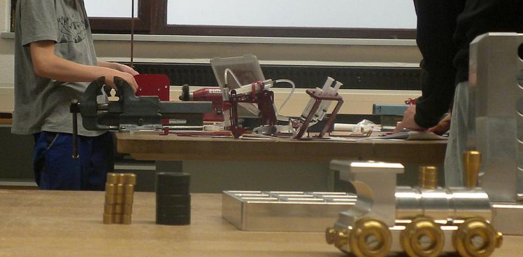 Metall_5_25 Bild zeigt einen Schüler bei einer Maschine in der Metallwerkstätte