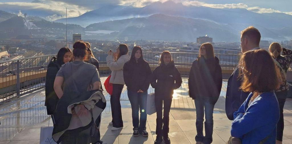 Bild zeigt Schülerinnengruppe auf einer Dachterrasse mit verschneitem Bergpanorama im Hintergrund