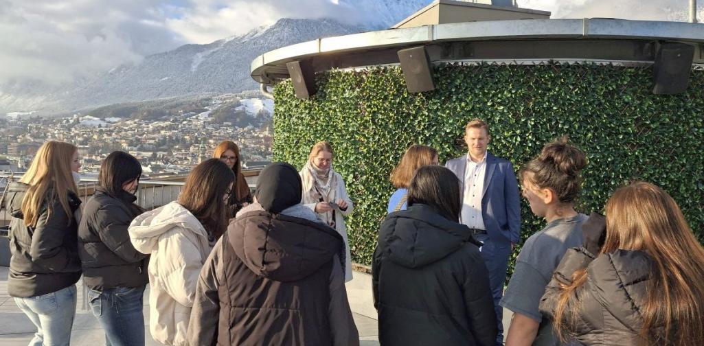 Schülerinnengruppe auf der Dachterasse des Hotel Adlers in Innsbruck im Hintergrund die verschneite Nordkette