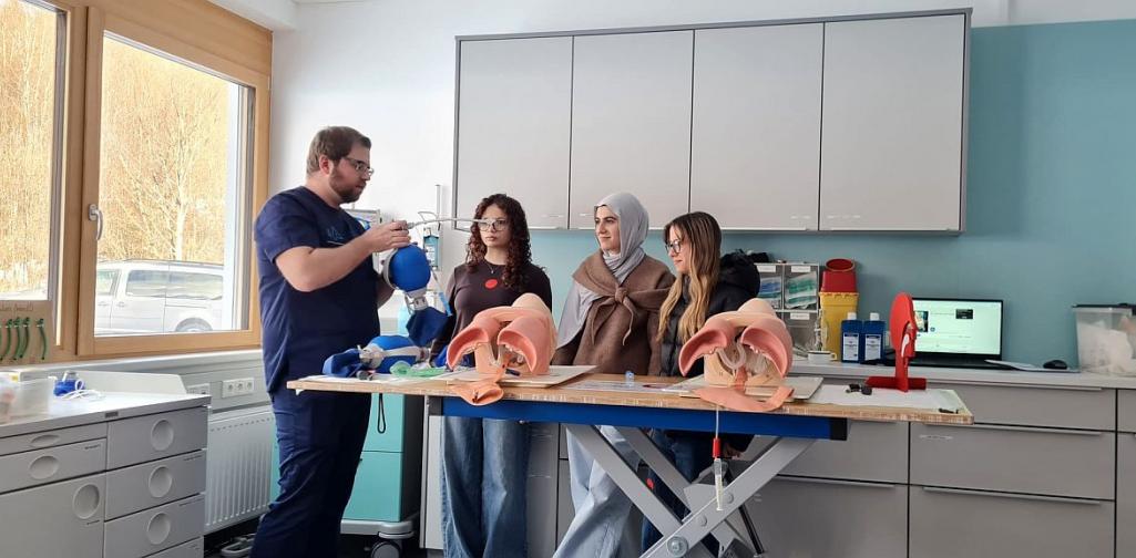 Bild zeigt drei Schülerinnen der Pflegegruppe und einen Ausbilder der die Atemwege anhand von Übungspuppen zeigt